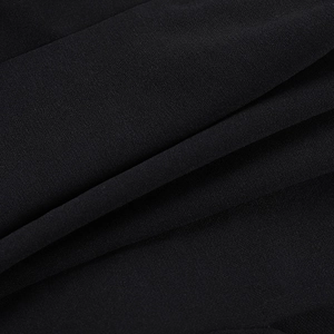 Gros plan détaillé de la texture du tissu crêpe noir et des plis délicats du haut