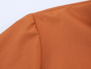 Gros plan détaillé des coutures et du tissu en popeline tissée sur une robe chemise orange