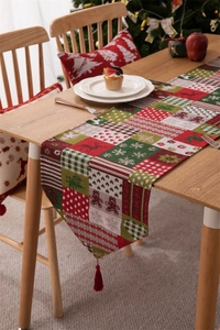 Dettaglio del runner da tavolo natalizio con motivi di renne e nappe rosse chic