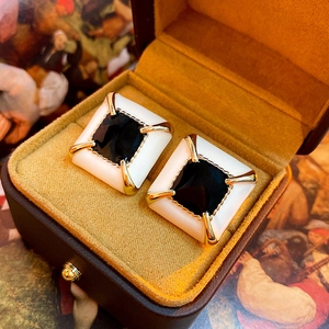 Close-up of vintage black and white enamel square earrings in a brown velvet jewelry box