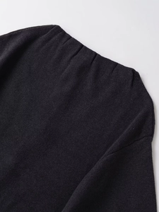 Détail du manteau en maille noire avec encolure minimaliste et texture de tissu mélangé