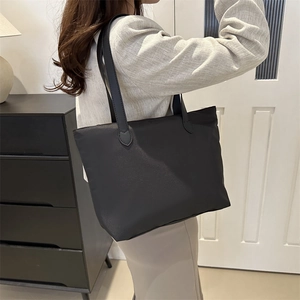 Minimalist black large capacity tote bag worn by a model in a modern home setting