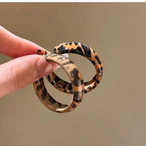 Close-up of geometric leopard print hoop earrings with a polished vintage finish