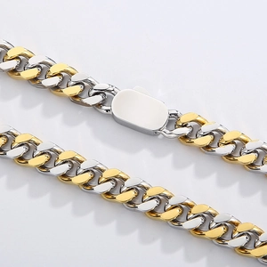 Macro view of two-tone gold and silver stainless steel Cuban chain with spring clasp