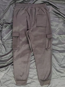 Detailed close-up of dark grey cargo sweatpants showing side pockets and elastic cuffs