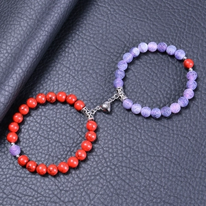 Détail de bracelets de couple en pierre naturelle rouge et violette à fermoir cœur