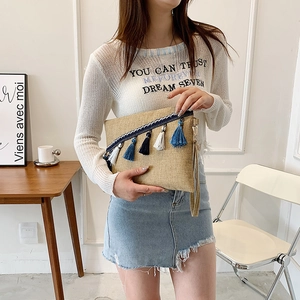 Women straw clutch bag with blue fringe tassels and wristlet in minimalist setting