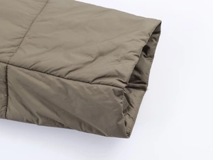 Gros plan détaillé de la veste matelassée vert olive montrant les finitions de qualité