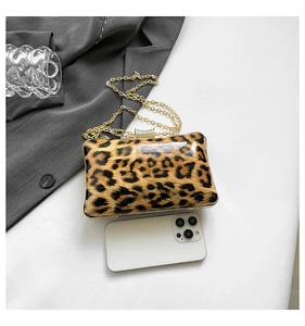 Detail view of leopard print clutch with gold chain strap and smartphone size reference