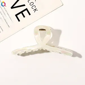 Macro detail of creamy white pearl finish hair claw clip with cross twist design