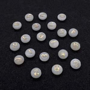 Dettaglio di perle bianche in conchiglia con numeri dorati 0-9 per creazione gioielli