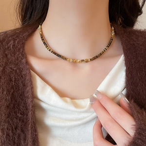 Detail of vintage tiger eye stone necklace with gold spacers on female model neck