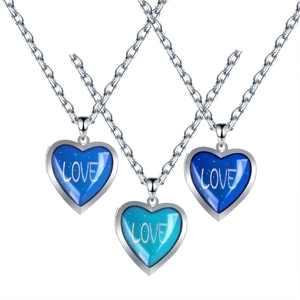 Macro detail of heart-shaped locket necklaces with color-changing blue inlay and gold Love text