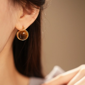 Vue détaillée de boucles d'oreilles en œil de tigre avec texture dorée vintage