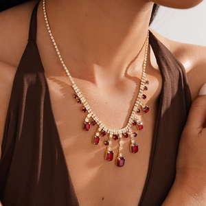 Close-up of luxury gold-tone necklace featuring rectangular red gemstones and fine diamonds