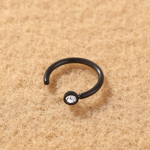 Close-up of a black stainless steel U-shaped nose ring with a clear round gemstone