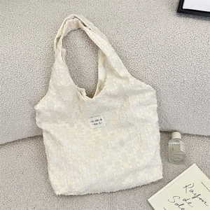 Detailed close-up of ivory jacquard lace texture and woven label on a canvas tote bag