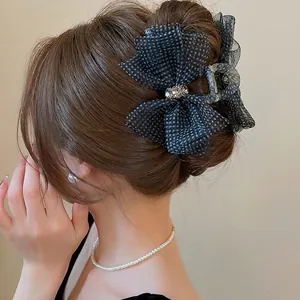 Elegant black polka dot mesh bow hair claw clip with rhinestones on brown hair