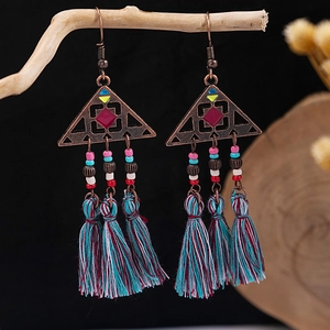 Macro shot of bohemian tassel earrings with turquoise beads hanging on a wooden branch