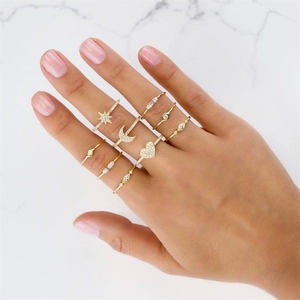 Set of gold-plated rings with zircon stars and moon shapes on white marble background