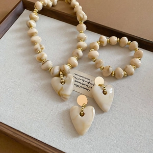 Detailed set of acrylic heart necklace, bracelet, and earrings in beige marble texture