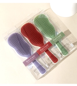 Three colorful detangling hair combs in purple, red, and green with retail packaging