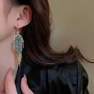 Elegant gold earrings with colorful rhinestones and long chain tassels worn by a model