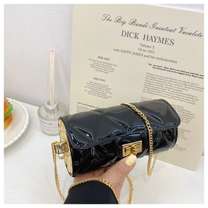 Detail of black patent quilted cylinder bag with gold chain and pearl clasp closure