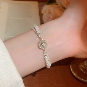Nahaufnahme eines doppelreihigen Armbands mit weißen Perlen und goldenem Sternanhänger