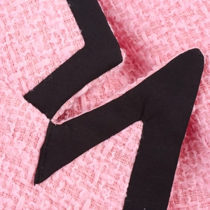 Nahaufnahme von rosa Tweed-Blazer-Stoff mit gewebter Textur und schwarzem Besatz