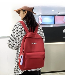 Detail of red nylon casual backpack with ATWF logo and purple Space Travel tag