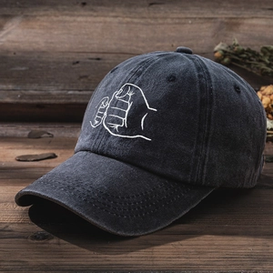 Close-up of fist-bump embroidery on washed denim baseball cap against rustic wood