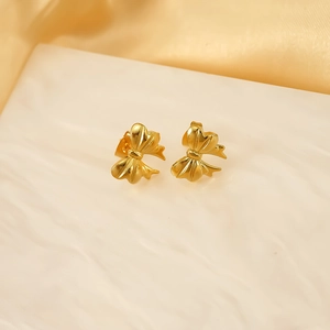 Macro view of gold bow-knot stud earrings featuring a polished 3D metallic texture