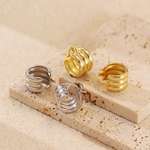 Detail of gold and silver layered S925 earrings on textured stone showing metal finish