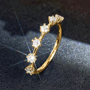 Detailaufnahme von fünf funkelnden Zirkoniasteinen auf einem schmalen goldenen Ring