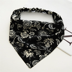 Dettaglio fascia elastica nera con motivo paisley e fiori su sfondo bianco