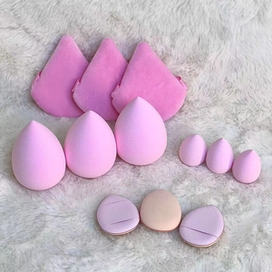 Set of 12 pink makeup sponges and finger puffs arranged on a soft white plush background