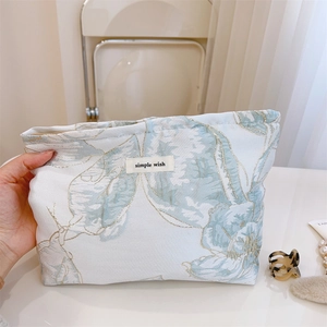 Gros plan sur la trousse à maquillage en jacquard avec broderie dorée et étiquette