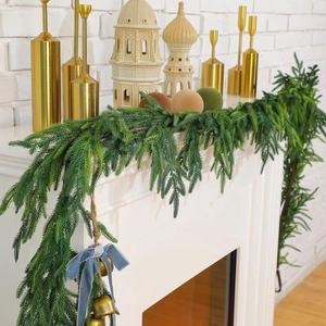 Artificial Norfolk pine garland with gold bells and blue ribbons on a festive fireplace
