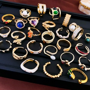 Close-up of golden adjustable zircon rings collection displayed on a black jewelry tray
