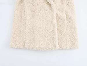 Detailed close-up of cream faux fur fabric texture and hem stitching on the coat