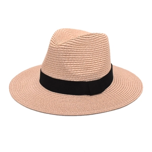 Detailed close-up of pink straw Panama hat with black ribbon band and textured weave