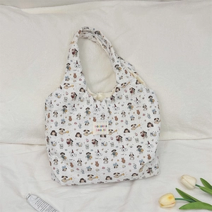 Detail of white quilted tote bag with colorful cartoon puppy patterns and fabric brand label