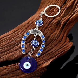 Ethnic horseshoe evil eye keychain featuring blue glass charms on a vintage metal frame