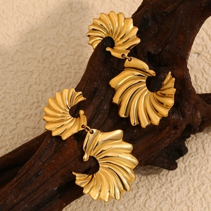 Détail macro de boucles d'oreilles ailes dorées 18K sur une texture boisée