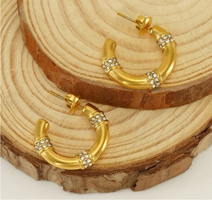 Close-up of gold-plated bamboo C-hoop earrings with sparkling zircon crystals on wood