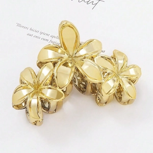 Three-piece set of gold metallic frangipani hair claws with polished finish shown on card