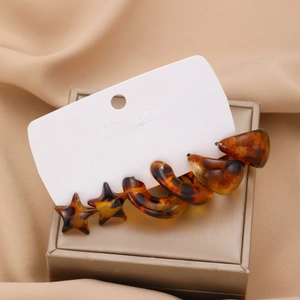 Detailed view of amber tortoise shell C-shaped resin earrings on satin and jewelry box