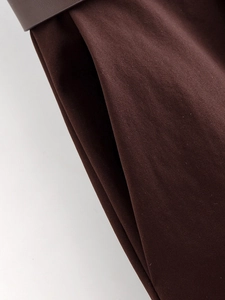 Dettaglio dei pantaloni marroni a gamba larga che mostra il tessuto twill e le cuciture