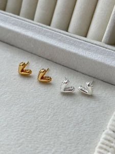 Macro shot of V-shaped gold and silver earrings on a gray velvet jewelry display box